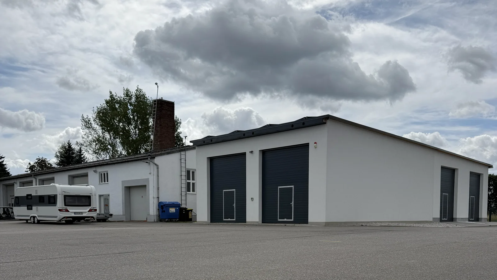 Halle mit zwei dunklen Toren und angrenzendem Gewerbegebäude