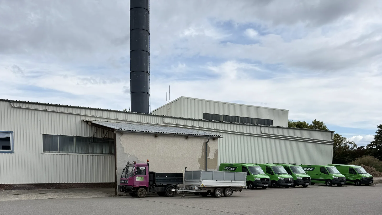 Gewerbehalle mit vorgelagertem Anbau und geparkten Firmenfahrzeugen